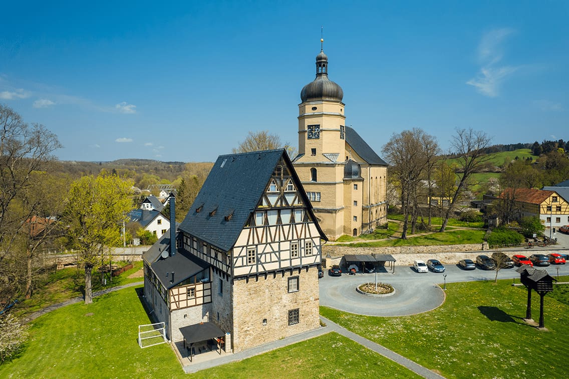 Eine Kirche und ein Umgebindehaus in Sachsen im Frühling