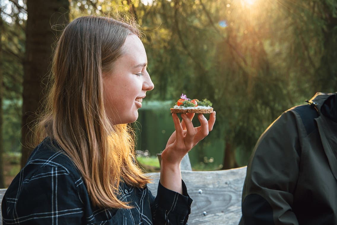 Ein Mädchen isst ein belegtes Brot im Wald