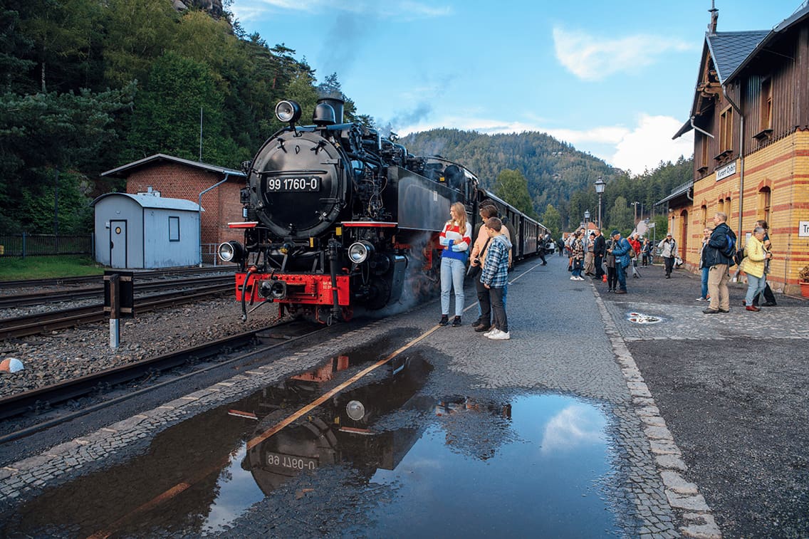 Kinder stehen vor einer alten Dampflokomotive in Deutschland.