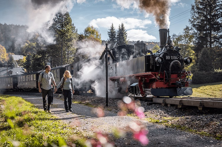 Ein Paar spaziert neben einer Eisenbahn in Sachsen.
