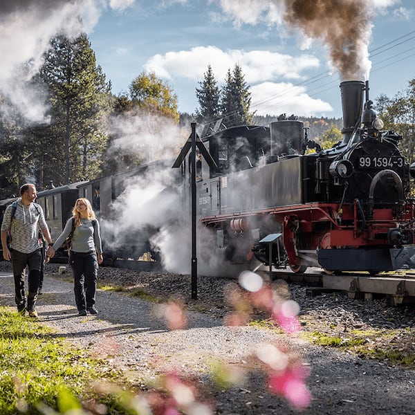 Ein Paar spaziert neben einer Eisenbahn in Sachsen.