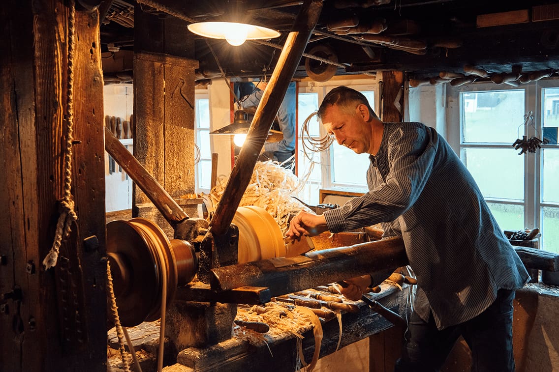 Eine alte Holzwerkstatt in Sachsen im Freilichtmuseum Seiffen, wo ein Mann drinnen steht und arbeitet.