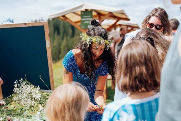 Eine Frau bereitet eine Blüte für die Erstellung eines Blumenkranzes vor.