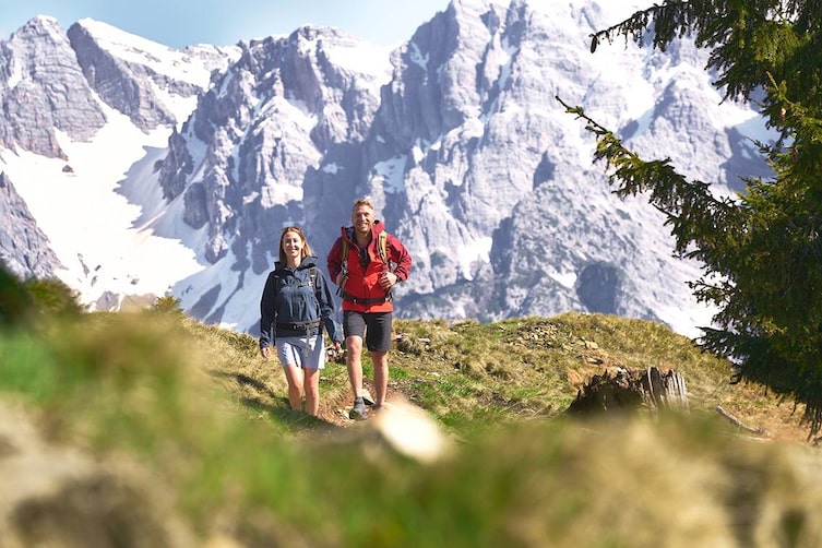 waldbaden in leogang, pärchen geht auf wiese, berg im hintergrund