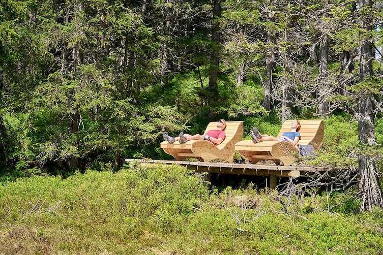 waldbaden in leogang, pärchen liegt auf holzliege in der natur