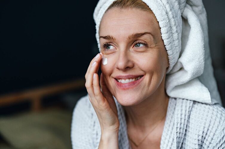 frau cremt sich ihr gesicht ein