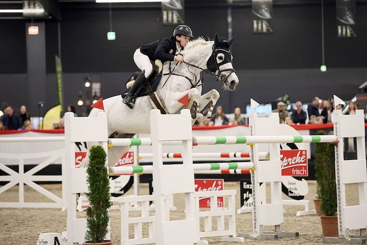 Ein Springreiter mitten im Sprung über ein Hindernis.