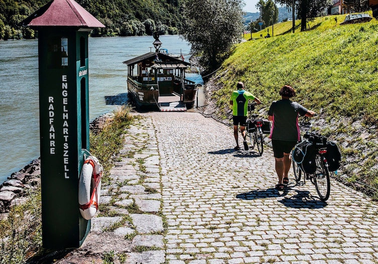 Zwei Radfahrer, die auf dem Weg zum Boot zur Donauüberfahrt sind.