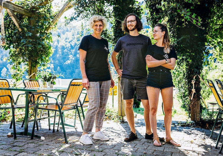 Eine Mutter steht mit ihrem Sohn und ihrer Tochter in einem Gastgarten an der Donau. Es ist Sommer, alle lächeln