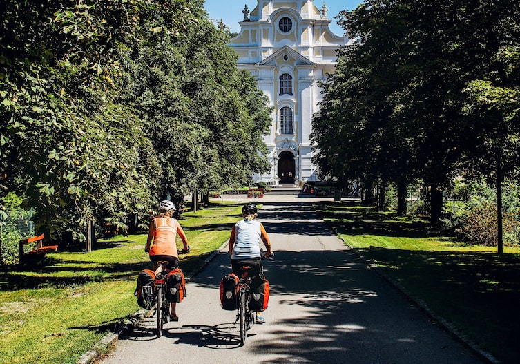 Zwei Radfahrerinnen radeln durch eine Allee in Richtung Stift Engelszell.