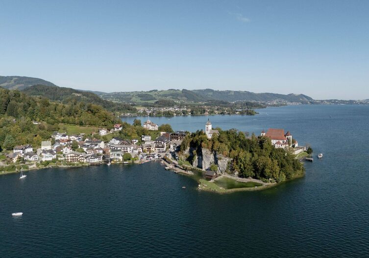Panoramaaufnahme vom Traunsee, mit Halbinsel und Kirchturm drauf.