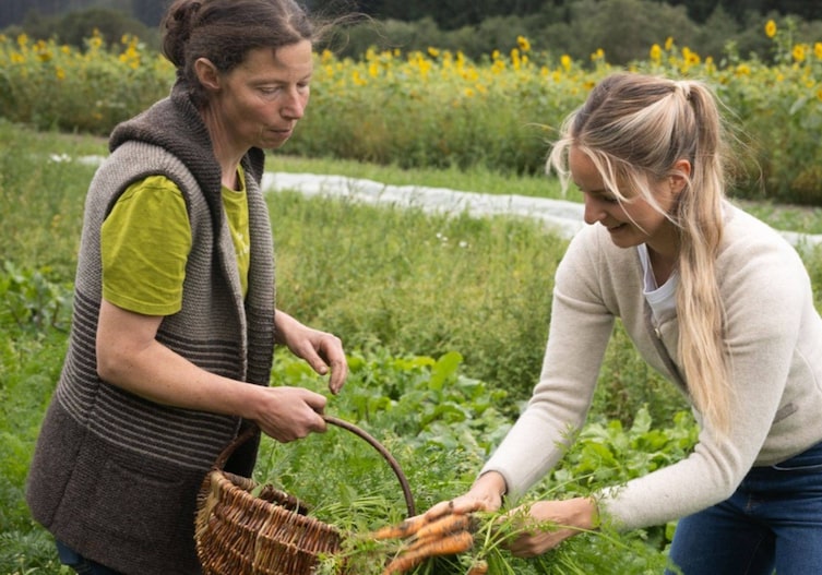 Paula Bründl und Sabine Prenn stehen auf einem Gemüsefeld und ernten Karotten und haben noch einen kleinen Weidekorb für den Transport mit.