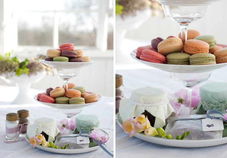 Macarons in unterschiedlichen Farben auf einer selbst gebastelten Etagere aus alten Sektgläsern und Tellern. Ganz unten in der Etagere stehen selbst gemachte Marmeladen