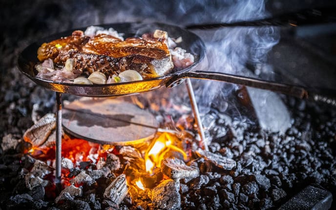Steak liegt in einer Eisenpfanne im offenen Feuer