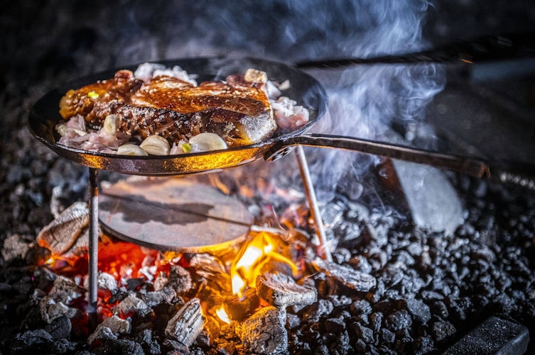 Steak liegt in einer Eisenpfanne im offenen Feuer