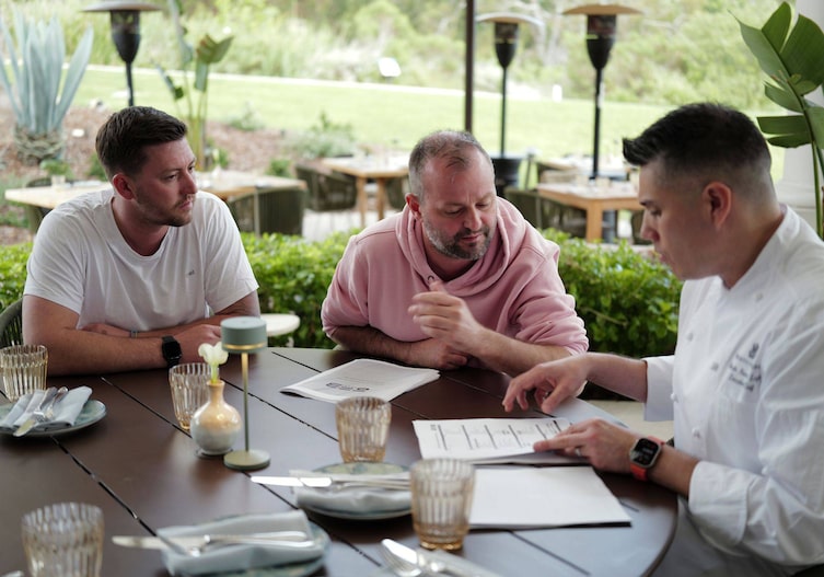 Fritz und Tamino Grampelhuber sitzen mit Chef Roberto Riveros Leyton vom Ritz Carlton an einem Tisch und sprechen miteinander.