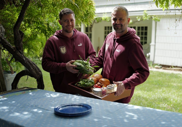 Fritz und Tamino Grampelhuber stehen im Garten vor einem Tisch mit einem Tablett frischer Zutaten für Burger.