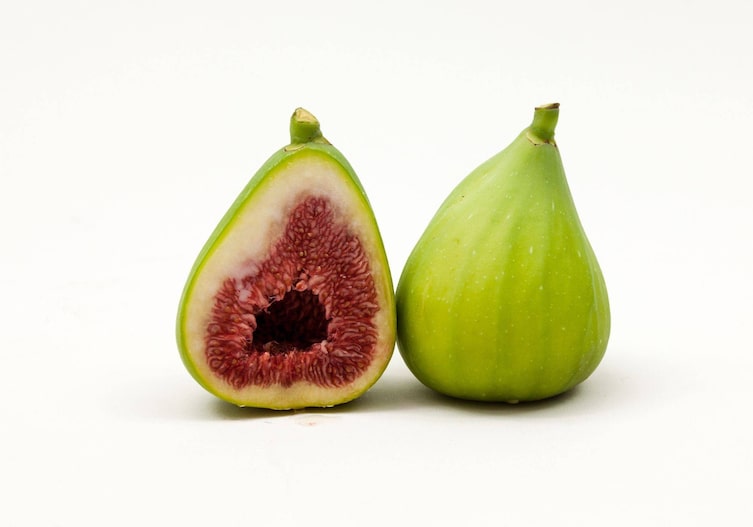 Feigensorte Dalamtie, eine reife Frucht durchgeschnitten einmal von vorne, einmal von hinten. Die Schale ist hellgrün, das Fruchtfleisch rot, sie sieht aus wie eine Birne.