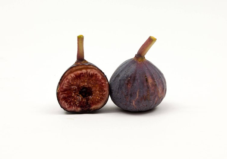blauviolette, rundliche Feige mit sehr saftigem Fruchtfleisch, halbiert, von vorne und von hinten fotografiert