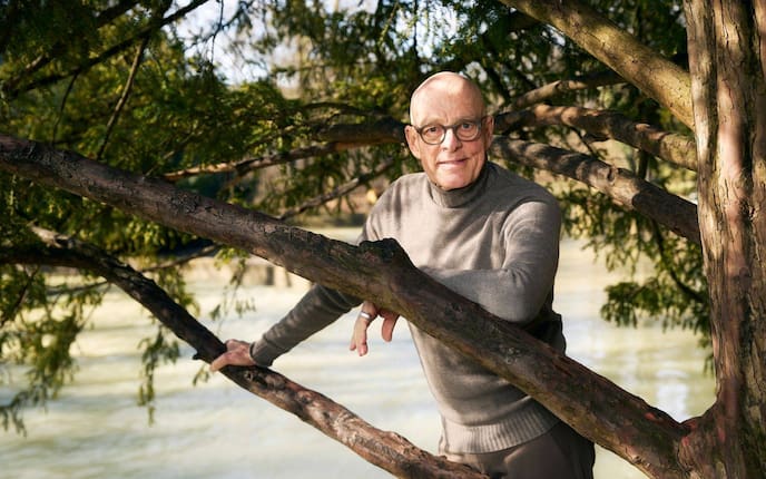 Dr. Ulrich Bauhofer steht hinter einem Baum, leht sich lächelnd an einen Ast mit dem Ellenbogen, dahinter ist ein breiter Fluss unscharf zu sehen.