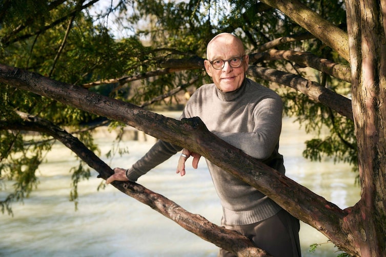 Dr. Ulrich Bauhofer steht hinter einem Baum, leht sich lächelnd an einen Ast mit dem Ellenbogen, dahinter ist ein breiter Fluss unscharf zu sehen.