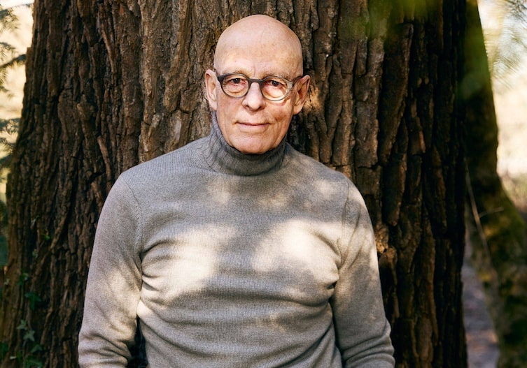 Dr. Ulrich Bauhofer lehnt an einem großen Baumstamm und lächelt in die Kamera