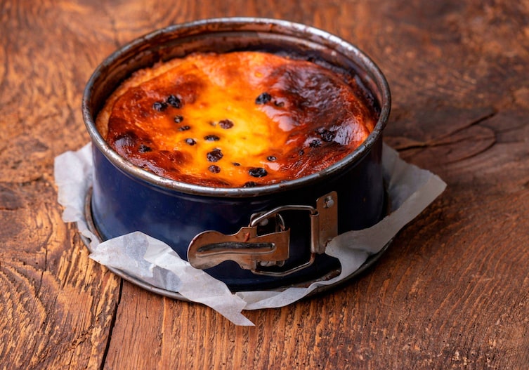 Springform mit einem fertigen Käsekuchen auf einer Holzunterlage