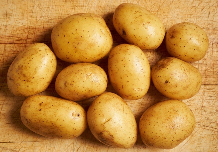 gewaschene Kartoffeln auf einem Holzbrett, mit rauer Schale