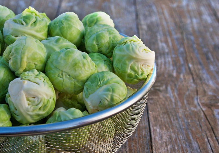 Kohlsprossen, Rosenkohl in einem Metallsieb auf einem Holzuntergrund