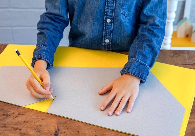 Kinderhände zeichnen die Schablone auf den Stoff für den Drachen.