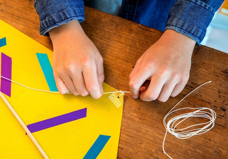 Kinderhände verknoten Schnüre am Drachen