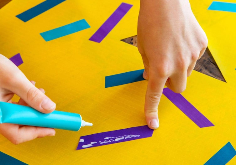 Der gelbe Drachen wird noch mit bunten Streifen beklebt.