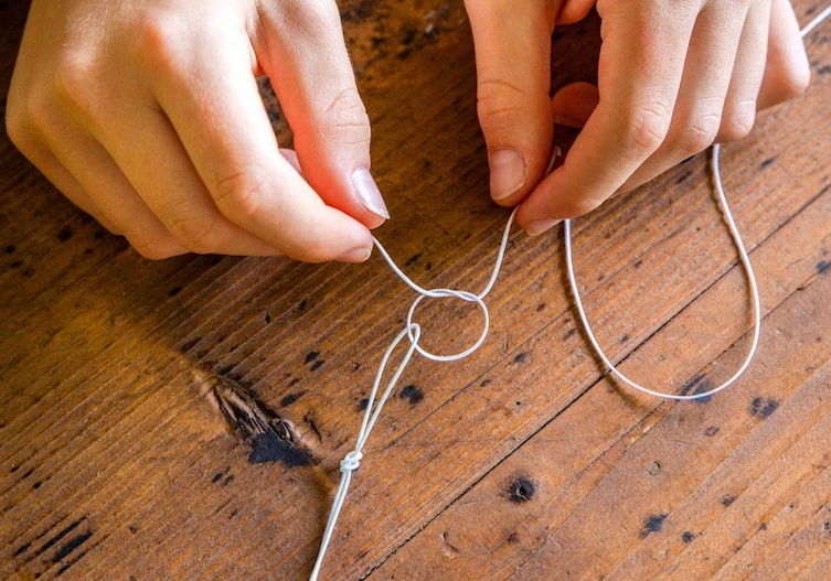 Fingerhände binden die Drachenschnur auf einem Holztisch