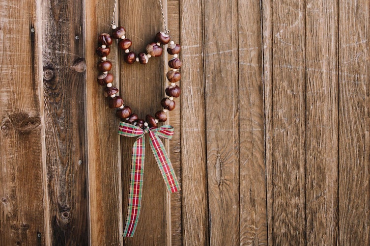 Kastanienherz hängt an einer Schnur auf einem Türgriff einer alten Holztür.
