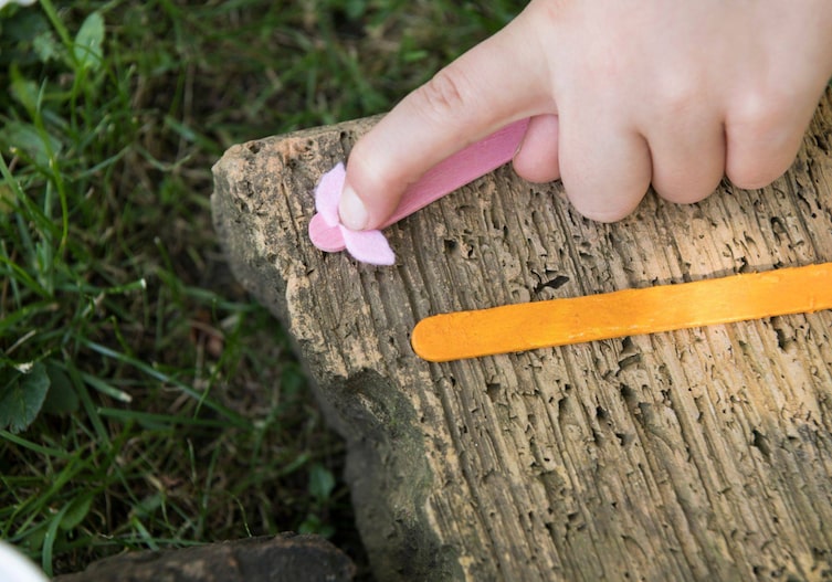 Kinderfinger drückt die kleinen rosa Filzteile (Ohren des Schweinchens) auf das rosa Eisstäbchen auf