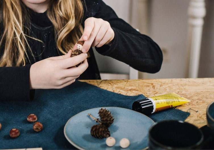 Kinderhände drücken den Holzkopf des Wichtels auf das Bockerl