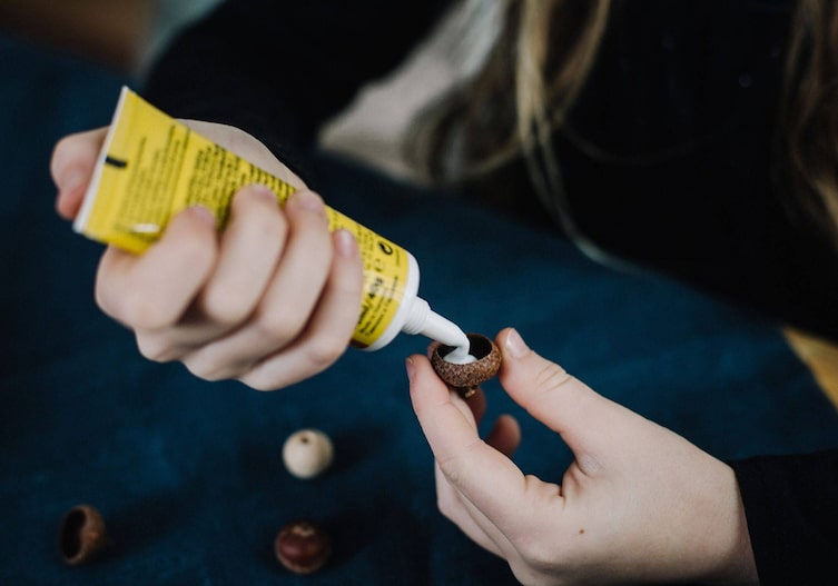 Eichelkappe wird von Kinderhänden mit einem Kleber aufgefüllt.