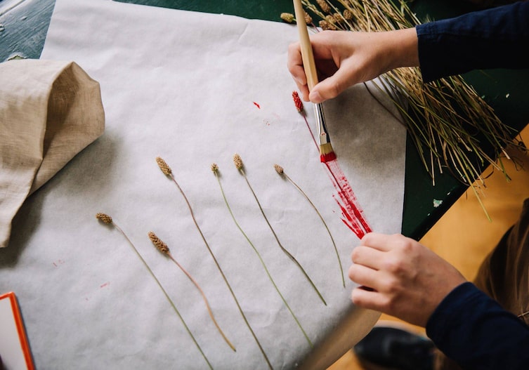 Getrocknete Blumen auf den Stoff legen und mit Farbe und einem Borstenpinsel wild über die Pflanzen streichen. So entsteht ein Abdruck.