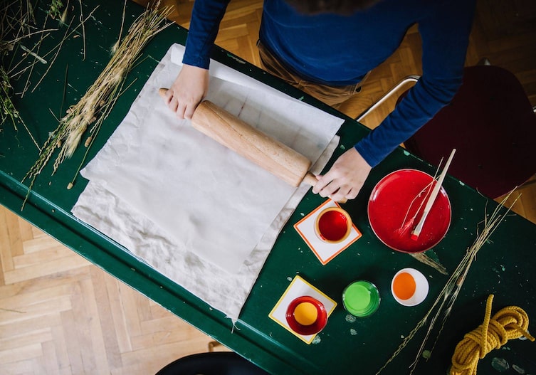 Die bunten Gräser werden auf dem Stoff mit einem Butterbrotpapier fixiert und mit einem Nudelwalker darübergerollt, um so einen Abdruck auf dem Stoff zu machen.