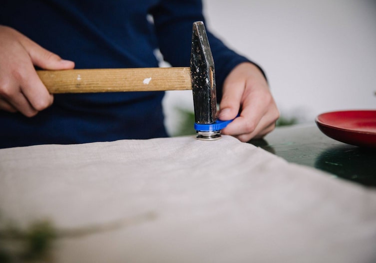 An den unteren Ecken des Turnsackerls mit dem Hammer die Ösen einschlagen.