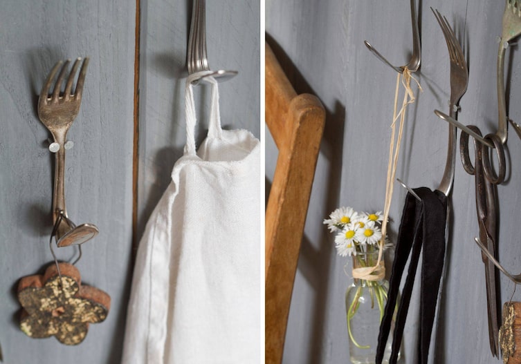 Alte Gabeln aller Art, deren Stiel umgebogen wurden und so als Wandhaken an der Wand befestigt werden können. Daran hängen Scheren, Holzschmuck, ein Geschirrtuch, oder eine kleine Glasvase mit Gänseblümchen.