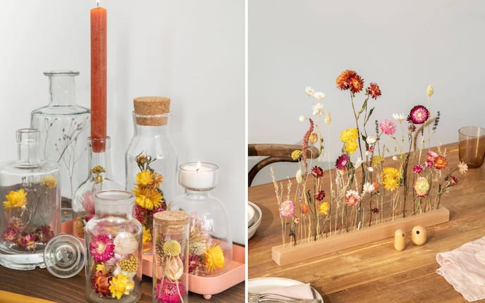 Bunte Trockenblumen in Gläser gefüllt und in eine Holzleiste gesteckt als Tischdeko.