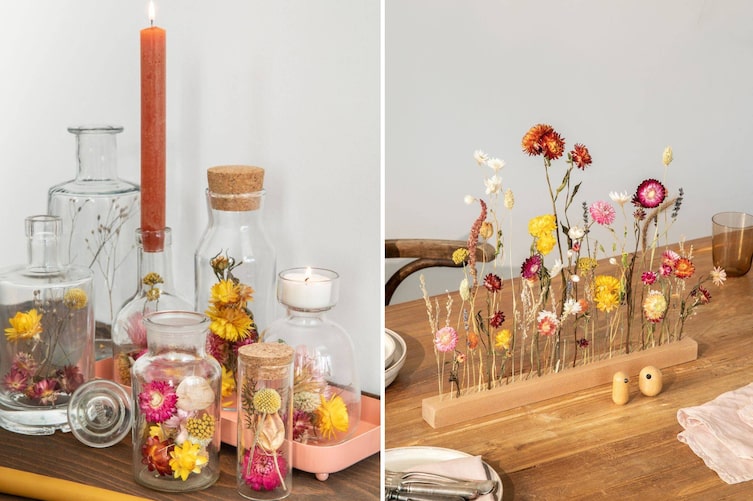 Bunte Trockenblumen in Gläser gefüllt und in eine Holzleiste gesteckt als Tischdeko.