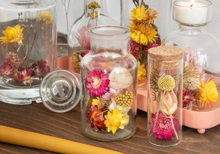 Nahaufnahme verschiedener Glasbehältnisse in der getrocknete bunte Blumen stecken.