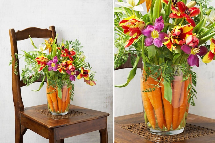 alter Holzstuhl, darauf steht eine Glasvase, die mit frischen Karotten gefüllt ist, darin stecken bunte Tulpen und Karottengrünzeug