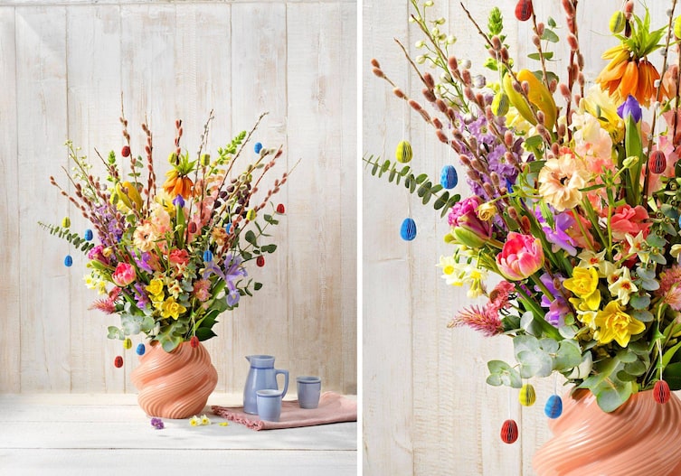 Bunter Frühlingsstrauch mit roten Palmkätzchenzweigen und kleinen Papierostereiern.