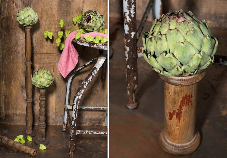 Artischockenherzen, die auf alten Holzkerzenständern oder alten Holzbeinen stehen.
