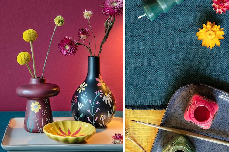 Blumenvasen, weinrot und schwarz, mit Blumenmotiven bemalt. Gelbe Keramikschüssel mit roter Blume. Daneben sieht man Keramikfarben und einen Pinsel auf einem Keramiktablett. Getrocknete Blumen und einen Teil einer grünen Stabkerze