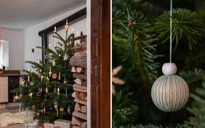 Christbaum in der Stube mit Holzboden, mit Holzchristbaumschmuck geschmückt, eine Holzkugel mit Stickgarn umwickelt in Nahaufnahme.