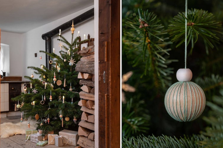 Christbaum in der Stube mit Holzboden, mit Holzchristbaumschmuck geschmückt, eine Holzkugel mit Stickgarn umwickelt in Nahaufnahme.